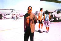 TV producer Chas. Floyd Johnson is on the set of 'JAG'  with U.S. Marine Corps Cobra gunship helicopters in the background.